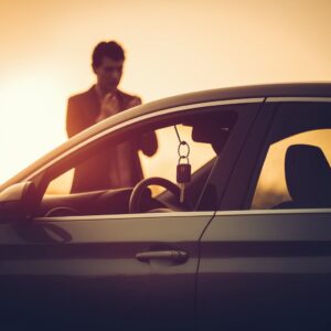 Car keys locked inside a vehicle with a worried person standing outside.